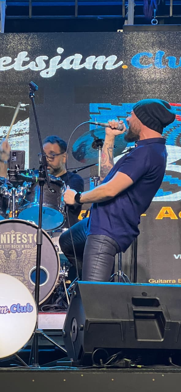 Vocalista do Bunkers ao microfone com o baterista ao fundo, no Manifesto Bar